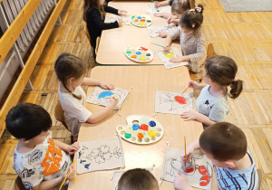 Dzieci kolorują farbami torebki z folkowymi wzorami.