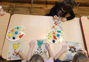 Dziewczynka maluje torebkę farbami.