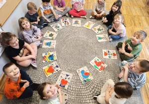 Dzieci siedzą w kole, przed nimi leżą pokolorowane torebki.