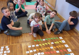 Zdjęcie przedstawia dziecko wykonujące działanie dodawania.