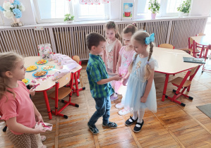 Chłopiec wręcza upominek swojej koleżance z grupy.