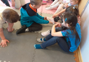 Chłopiec przymierza pantofelka jednej z dziewczynek.