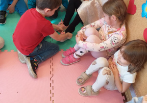 Chłopiec przymierza pantofelka jednej z dziewczynek.