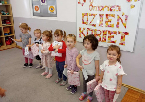 Dziewczynki stoją naprzeciwko chłopców z otrzymanymi prezentami.