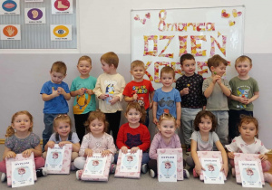 Grupa pozuje do zdjęcia na tle napisu dzień Kobiet z otrzymanymi upominkami.