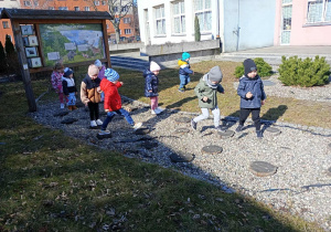 Dzieci oglądają ślady dzikich zwierząt odciśniętych na pniach drzew.
