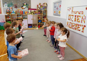 Dziewczynki stoją naprzeciwko chłopców, którzy trzymają prezenty w dłoniach.