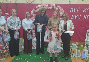 Dziewczynka pozuje do zdjęcia z jury.