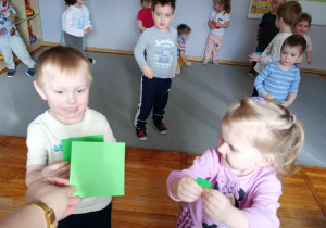 Dzieci trzymające zielone kwadraty w dłoniach.