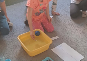 Dziewczynka wrzuca kamień do wody.