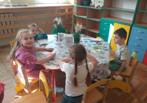 Dzieci pakują mydełko do pięknie przyozdobionych torebeczek.