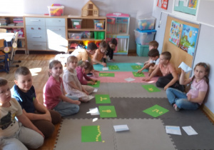 Dzieci wkładają do zielonego portfela tyle monet ile wskazuje podana przez nauczyciela liczba.