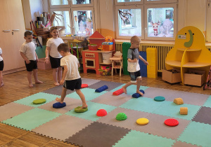 Dzieci chodzą gołymi stopami po ścieżce sensorycznej.