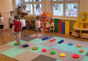 Dzieci chodzą gołymi stopami po ścieżce sensorycznej.