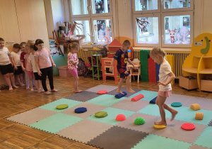 Dzieci chodzą gołymi stopami po ścieżce sensorycznej.