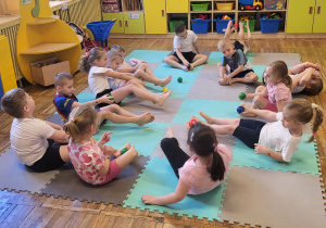 Dzieci ćwiczą stopy z wykorzystaniem piłeczek sensorycznych.