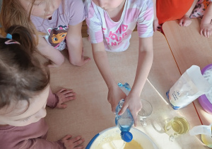 Dziewczynka wlewa wodę gazowaną do miski z ciastem.