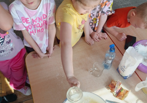 Dziewczynka wsypuje odmierzoną porcję mąki do miski.
