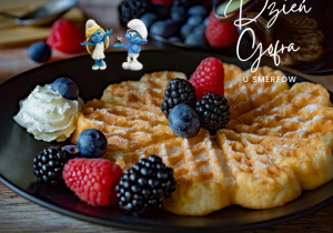 Grafika przedstawia zdjęcie gofrów z dodatkami i napis Dzień Gofra u Smerfów