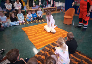 Dziecko wykonuje czynności ratujące życie na fantomie.