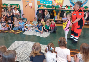 Ratownik medyczny instruuje dzieci jakie czynności należy wykonać jeśli ktoś się zakrztusi.