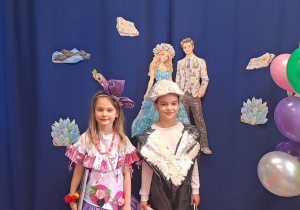 Dziewczynka z chłopcem pozują do zdjęcia w swoich strojach i upominkami.