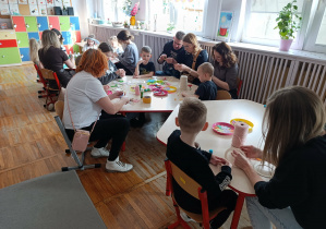 Zdjęcie przedstawiające rodziców wraz z dziećmi podczas wykonywania ozdób wielkanocnych.