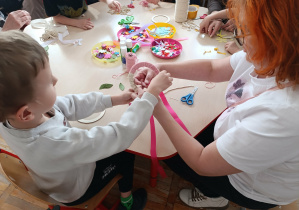 Chłopiec wraz z babcią wykonują ozdobę wielkanocną.
