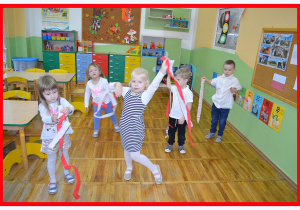 Dzieci z grupy Misie tańcza patriotyczny taniec z szarfami w kolorach białym i czerwonym.