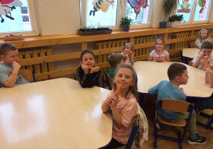 Zdjęcie przedstawia dzieci zajadające marchewkę.