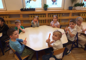 Zdjęcie przedstawia dzieci zajadające marchewkę.