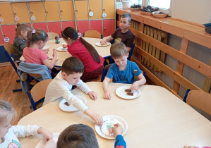 Na zdjęciu widzimy dzieci z grupy Odkrywcy podczas dekorowania ciastek czekoladą.