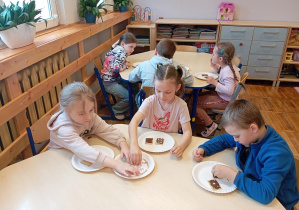 Na zdjęciu widzimy dzieci z grupy Odkrywcy podczas dekorowania ciastek czekoladą.