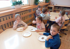 Dzieci z grupy Odkrywcy jedzą słodkie ciasteczka.