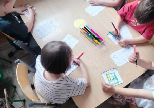 Dzieci kolorują przy stoliku.