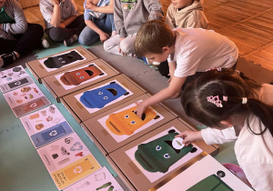 Dzieci wrzucają śmieci do odpowiednich pojemników.