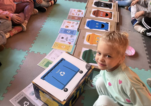 Dziewczynka wrzuca śmieci do odpowiedniego pojemnika.