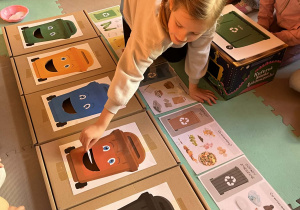 Dziewczynka wrzuca śmieci do odpowiedniego pojemnika.