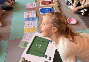 Dziewczynka wrzuca śmieci do odpowiedniego pojemnika.