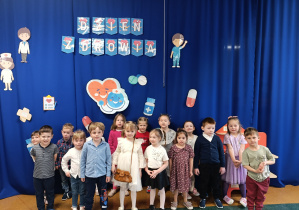 Dzieci z grupy Stokrotki pozują do pamiątkowego zdjęcia na tle dekoracji.