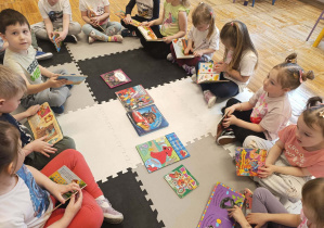 Dzieci z grupy Stokrotki oglądają przyniesione do przedszkola książki z bajkami.