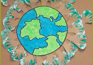 Grupowa praca plastyczna – kontur ziemi otoczony drzewami stworzonymi z odrysowanych dłoni i pomalowanych farbą koron drzew.