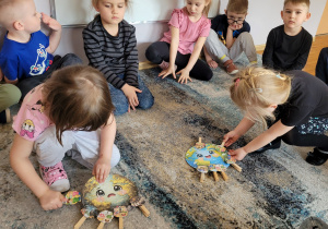 Dziewczynki siedzą na dywanie podczas zabawy klamerkowej.