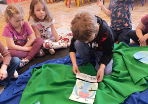 Chłopiec układa puzzle z napisem dzień ziemi i obrazkiem planety.