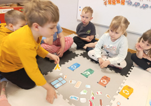 Dzieci segregują śmieci przy użyciu sylwet koszy w odpowiednim kolorze.