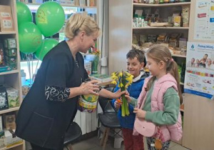 Dzieci z grupy Motylki wręczają kwiaty oraz częstują się zdrowymi lizakami.