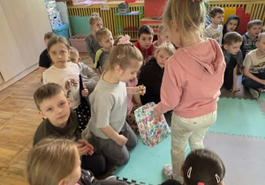 Dziewczynka częstuje starszych kolegów cukierkami.