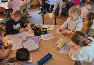 Dzieci siedzą przy stolikach, samodzielnie wykonują książeczkę.