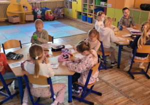 Dzieci siedzą przy stolikach, samodzielnie wykonują książeczkę.