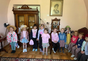 Dziewczynki pozują do zdjęcia na tle eksponatów muzealnych.